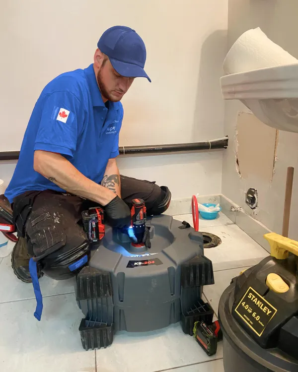 A Superior Plumbing & Heating plumber running a drain machine on a bathroom floor